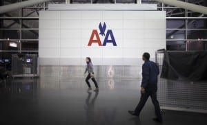 People walk past an American Airlines logo at John F. Kennedy (JFK) airport in in New York