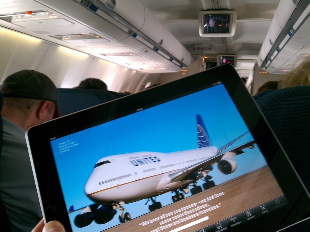 A passenger reads an article about United Airlines on his iPad while on an United flight. 