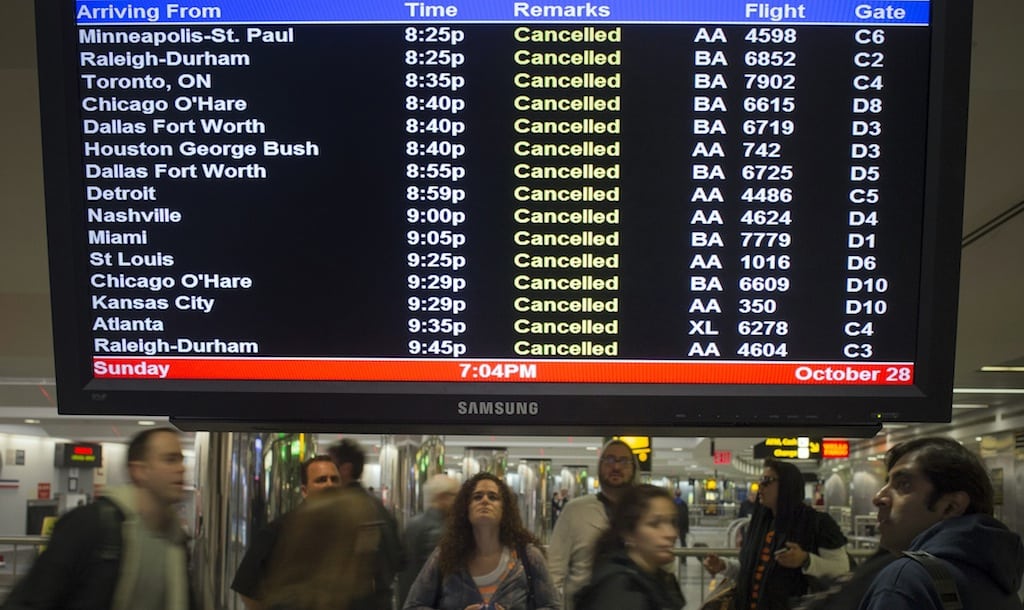 Travellers surround a flight monitor showing cancelled flights at LaGuardia airport in New York October 28, 2012.