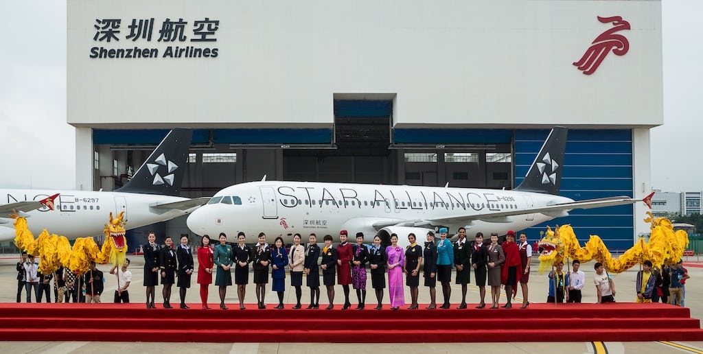 Staff from Star Alliance member airlines stand on the tarmac at Shenzhen Bao’an International Airport in front of two Shenzen Airlines' Star Alliance branded Airbus A320s. 