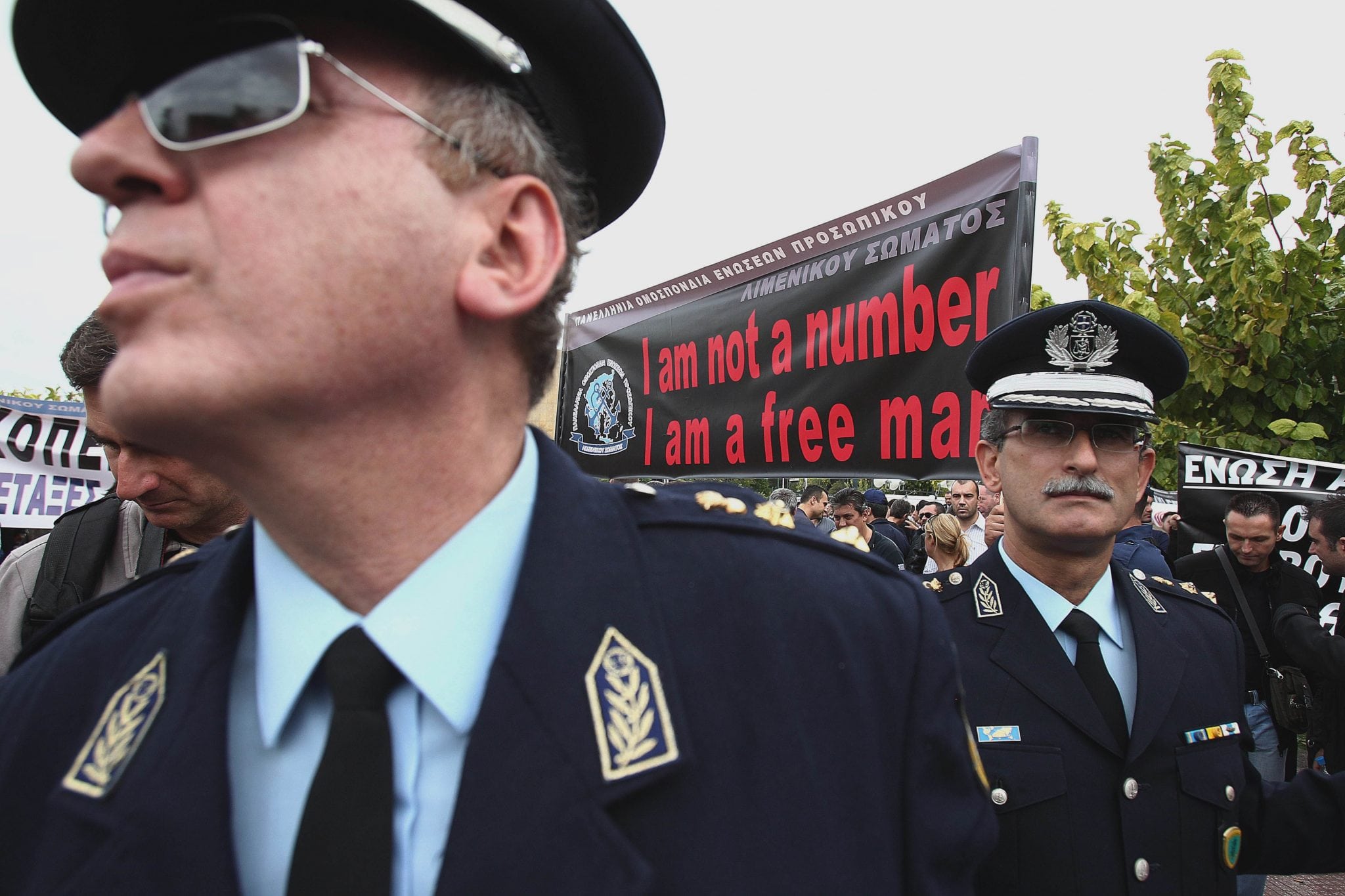 Police officers stand in front of a banner during a protest in central Athens on Thursday, Nov. 1, 2012. 
