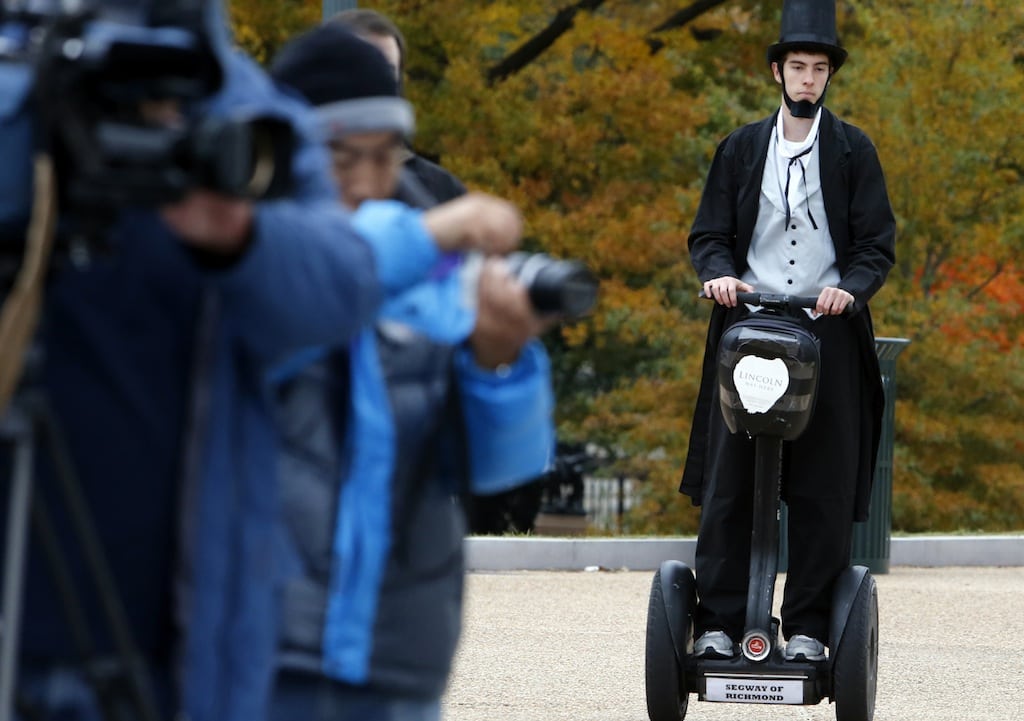 As members of the media, left, wait, Christopher Brady, dressed as Abraham Lincoln, arrives on a Segway at the launching ceremony of the Lincoln Movie Trail at the State Capitol in Richmond, Va. Thursday, Nov. 15, 2012. 
