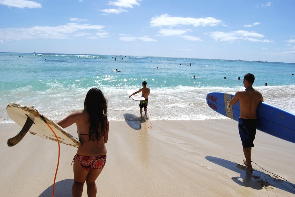 Surfers along a beach in Oahu, Hawaii.
