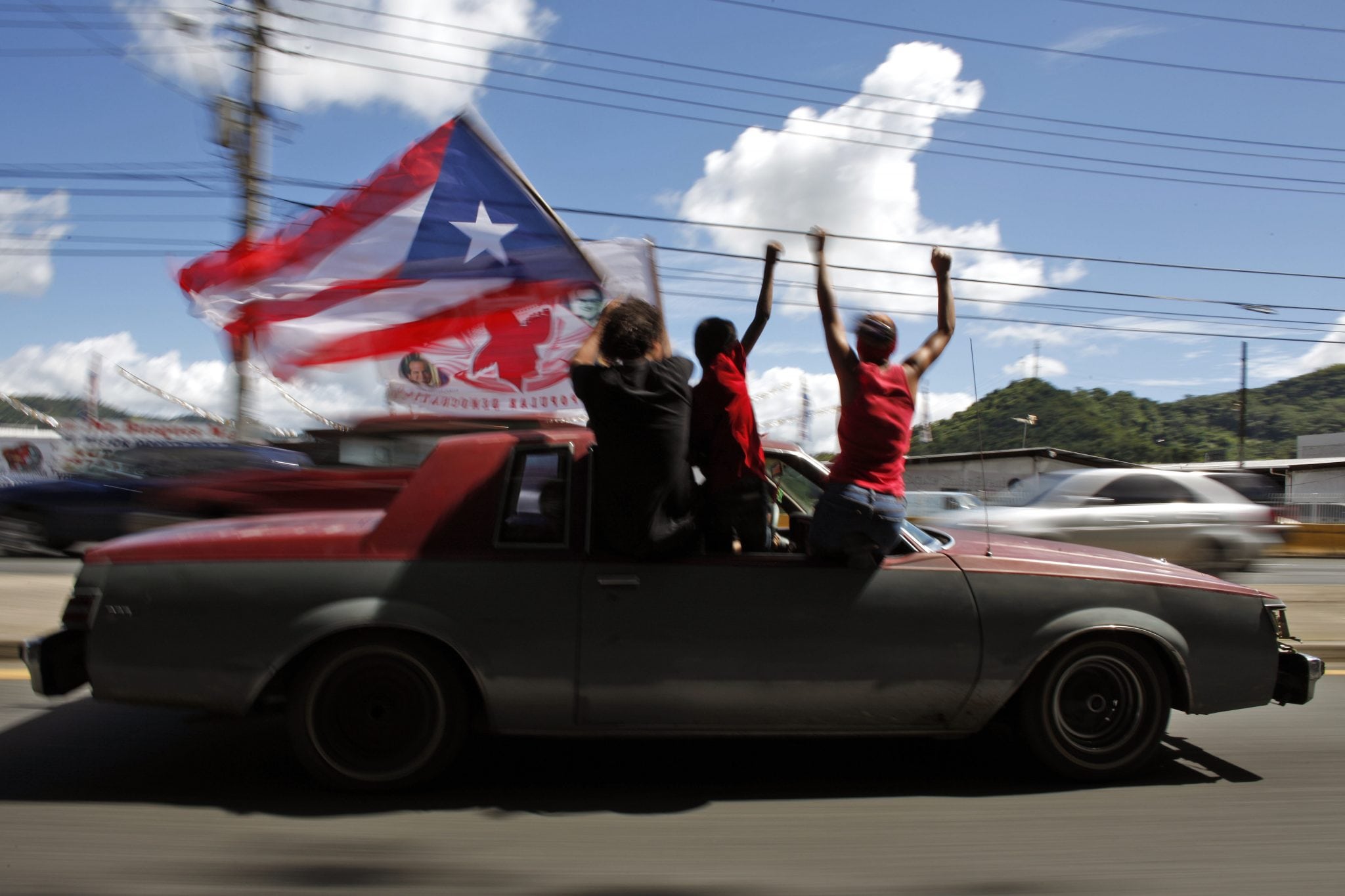 People ride atop a vehicle waving a Puerto Rican flag during elections in San Juan, Puerto Rico, Tuesday, Nov. 6, 2012. 