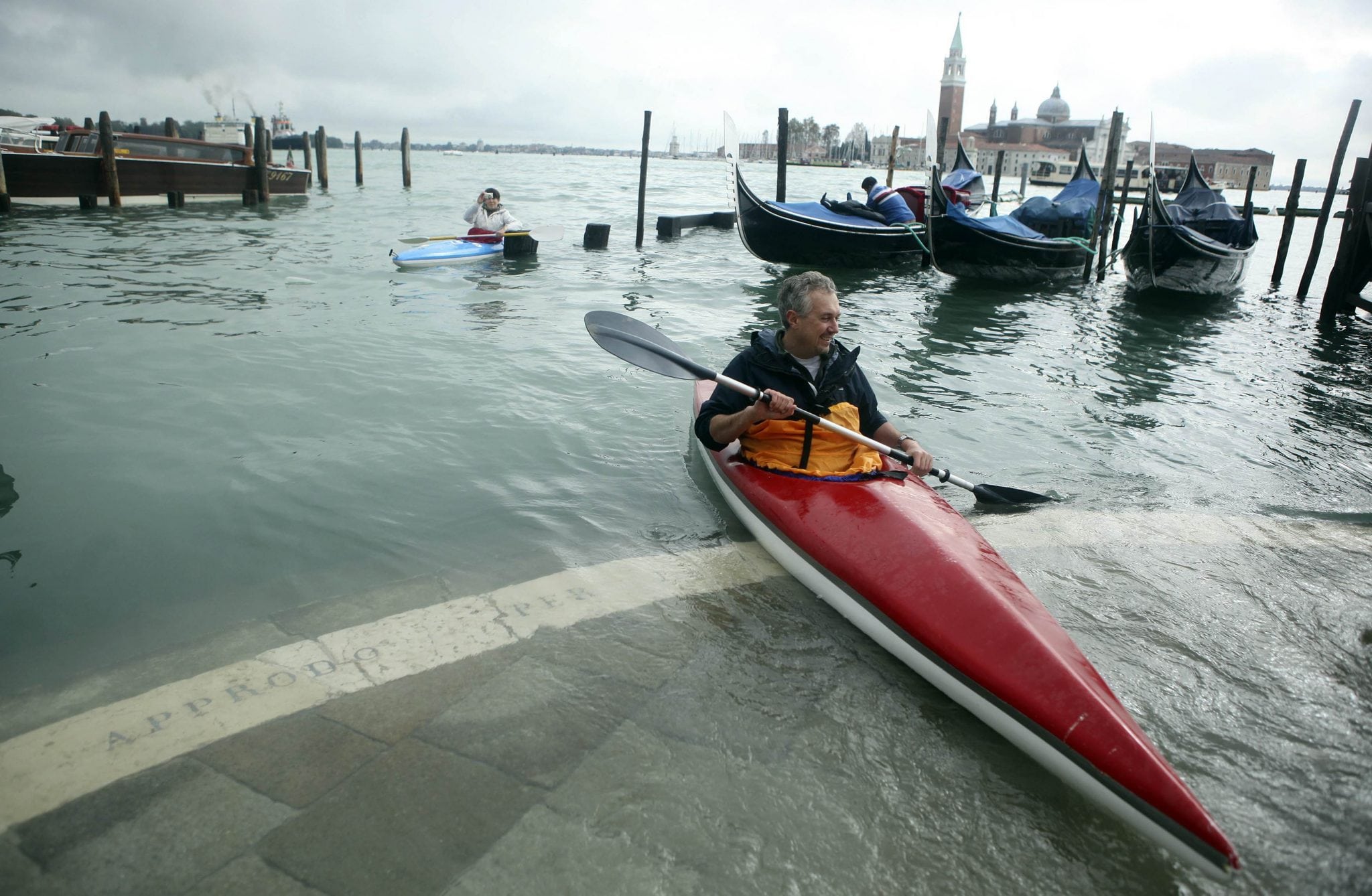  A man rows a kayak in front of flooded St. Mark's Square during a period of seasonal high water in Venice.
