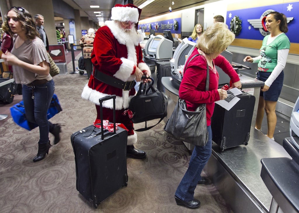 In this Wednesday, 21, 2011, file photo, holiday travelers, including Donald Occimio of Mesa, Ariz., dressed as Santa Claus, and his wife Diane check in at Sky Harbor International Airport, in Phoenix. 
