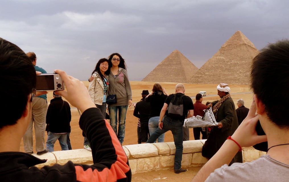 Somewhere in here, the travel industry sees a cliche. Chinese tourists at the pyramids in Egypt. 