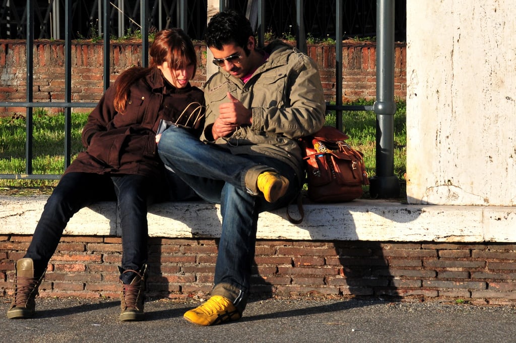 A Roman couples sits together looking at cell phone at the castle grounds of the Castel Sant'Angelo. 
