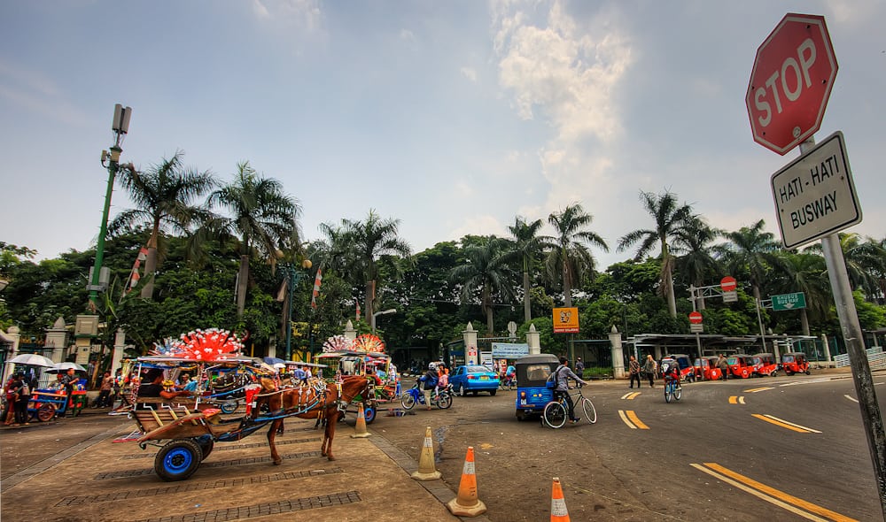 Horse-drawn carts and taxis awaiting tourists in Jakarta, Indonesia. 