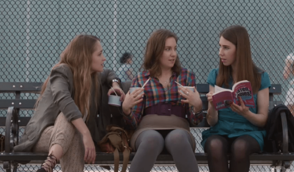 Hannah, Jessie, and Shoshanna eat frozen yogurt on a park bench. 