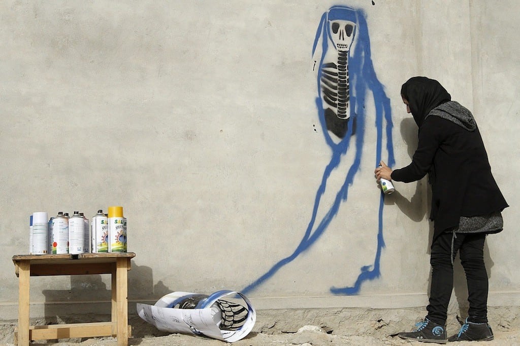 Afghan artist Malina Suliman paints graffiti on a wall in Kandahar city December 30, 2012. 