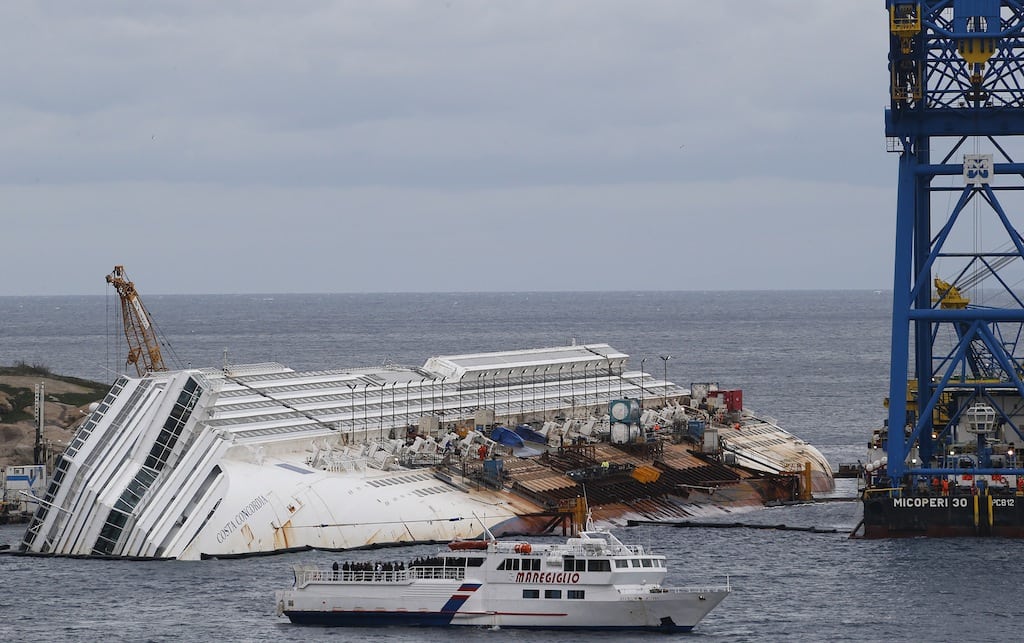 Relatives of victims stand on a ferry in front of the capsized cruise liner Costa Concordia outside Giglio harbour January 13, 2013. Sunday marks the first anniversary of the Costa Concordia shipwreck in which 32 people died.  