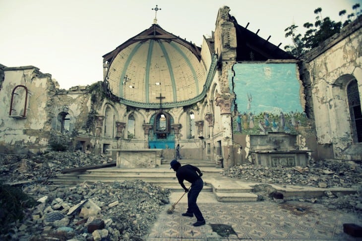 In this Jan. 12, 2013 file picture a man sweeps an exposed tiled area of the earthquake-damaged Santa Ana Catholic church, where he now lives, in Port-au-Prince, Haiti.