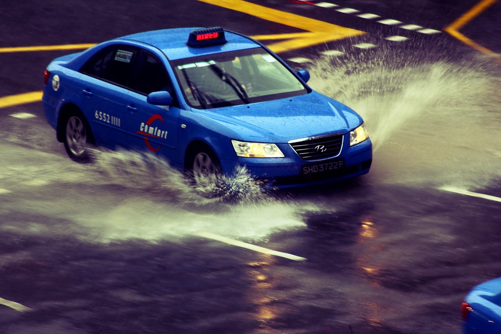 A Comfort Hyundai Sonata taxi rushing through a massive puddle of water along Rochor Road, Singapore. 