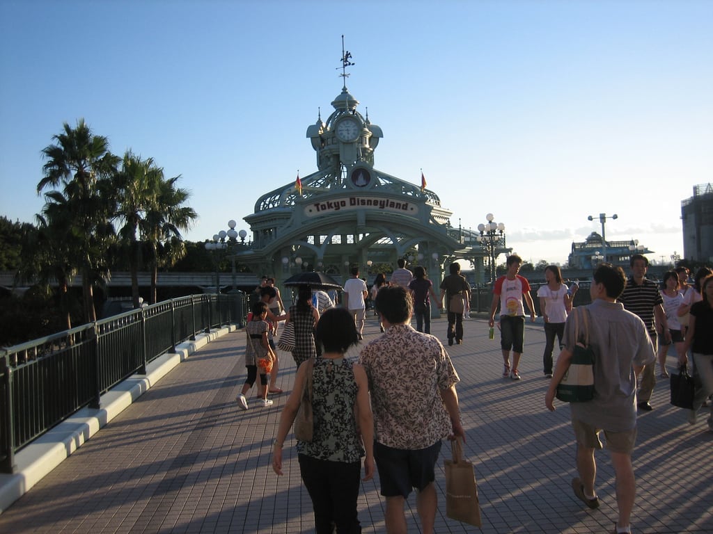 Tourists walk into Tokyo Disneyland, whose third quarter earnings exceeded forecasts on visitor numbers. 