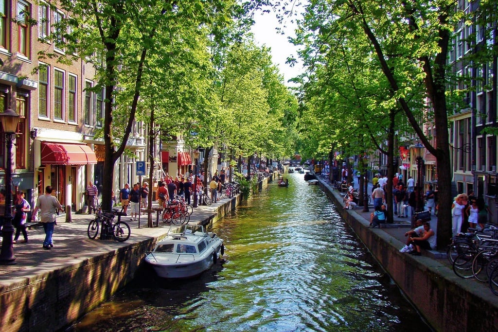 Residents and tourists linger around the canal on a spring day in Amsterdam. 