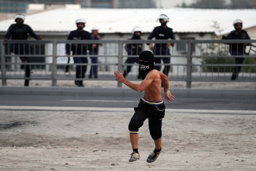 A masked Bahraini anti-government protester confronts riot police who give chase in Sanabis, Bahrain, Tuesday, Feb. 12, 2013. 