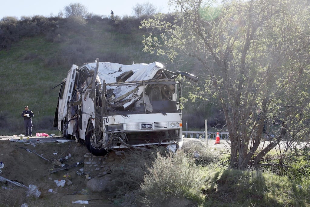 In this Feb. 4, 2013 file photo, an official takes notes at the scene of a tour bus crash near San Bernardino, Calif.