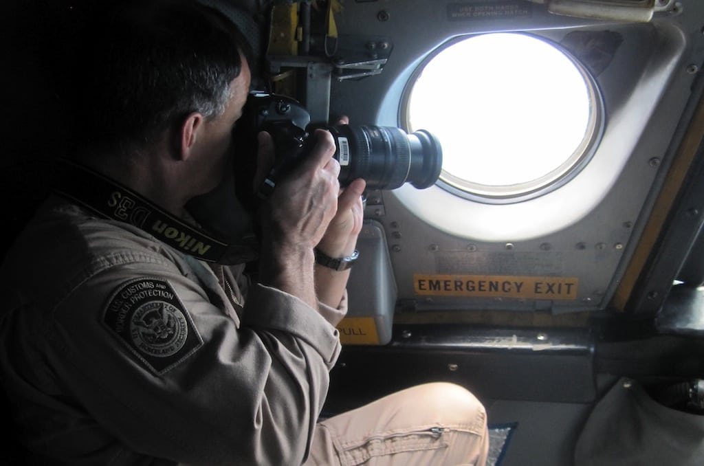 In this Jan. 25, 2013 photo, a detection officer with U.S. Customs and Border Protection takes photos of a potential drug-carrying boat from inside a P3 Orion Airborne Early Warning Aircraft while flying over waters near the Pacific coast of Costa Rica. 