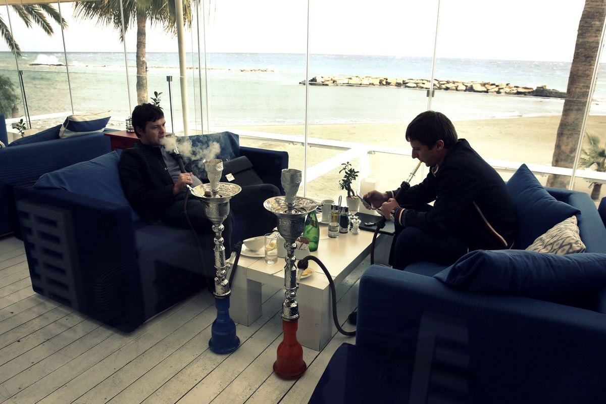 Two Russian businessmen smoke from hookahs inside a restaurant in Limassol, a coastal town in southern Cyprus February 20, 2013. 