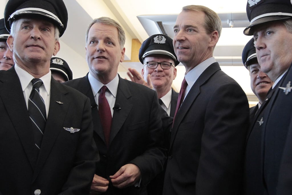 Pilots from both airlines gather for a photo with Doug Parker, left, of U.S. Airways and Tom Horton of American Airlines after the announcement of the airlines' merger during a news conference at Dallas-Fort Worth International Airport, Thursday, February 14, 2013. 