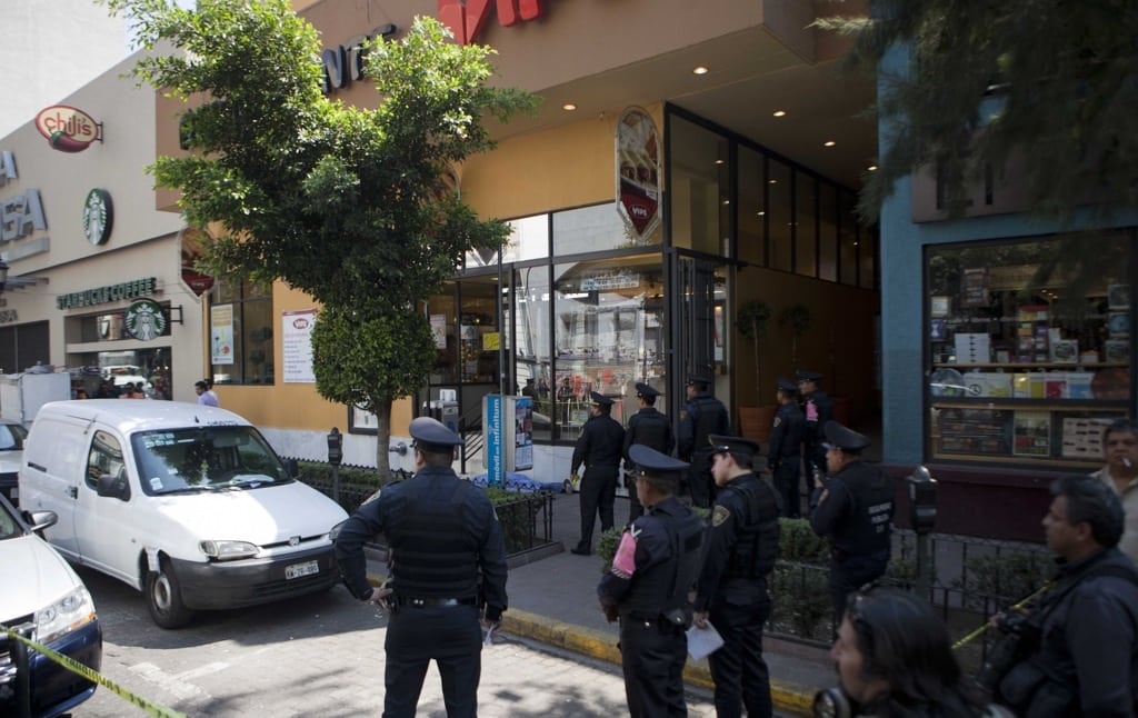 Police block the sidewalk where the covered body of an unidentified man, center, lays on the sidewalk in the Zona Rosa neighborhood of Mexico City, Friday, Feb. 15, 2013. 
