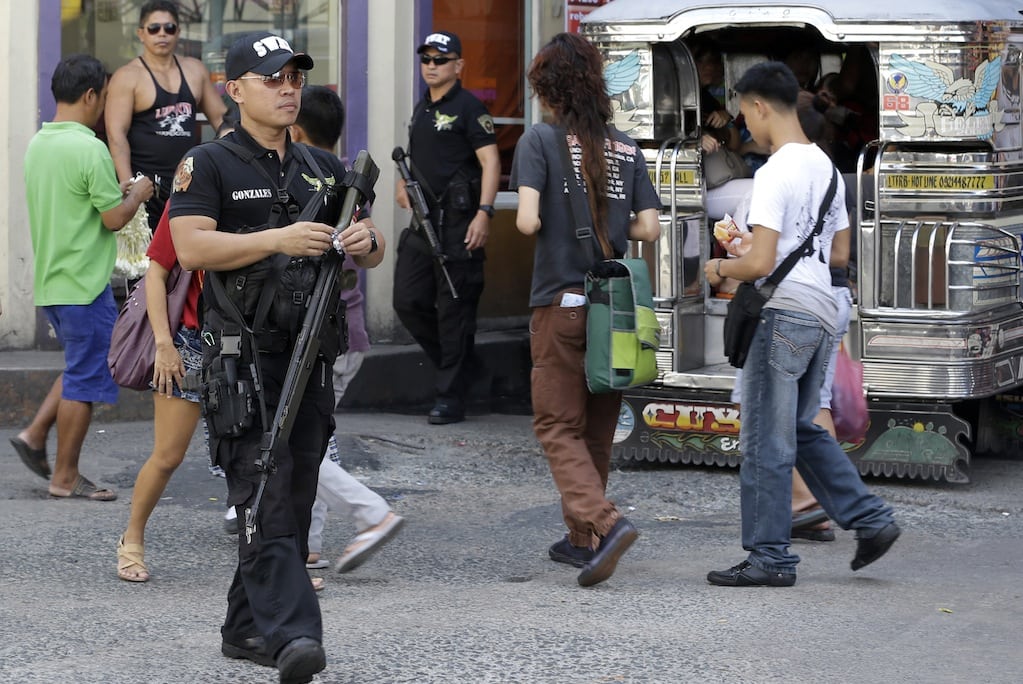 In this Friday Feb. 1, 2013 photo, Pasay city SWAT members of the Philippine National Police make the rounds of business establishments as they go on patrol at suburban Pasay city, south of Manila, Philippines. 