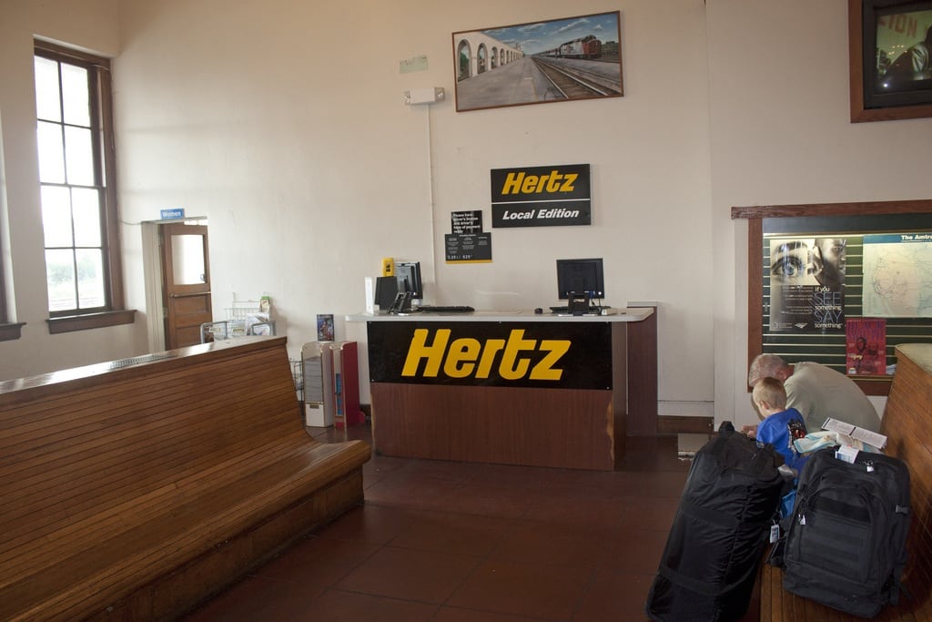 No one behind the desk? No problem. Hertz is installing video kiosks at off-airport locations. Pictured is a Hertz Local Edition off-airport location in Orlando, but the branding will change to Dollar Thrifty. 