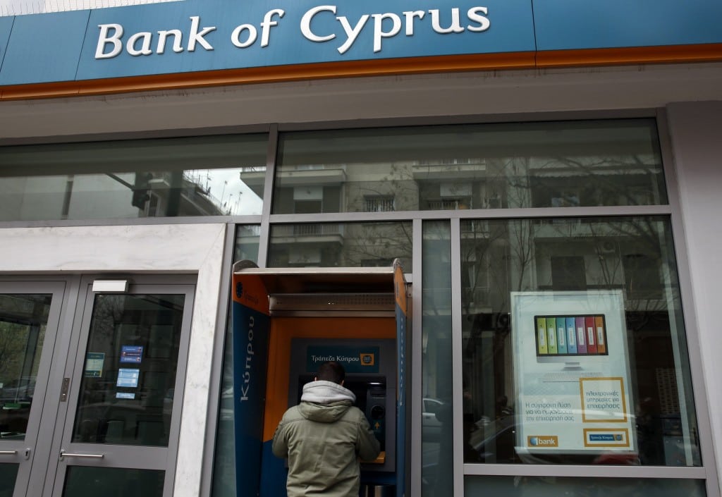 A man withdraws money from an automatic teller machine at a branch of Bank of Cyprus in Athens. 