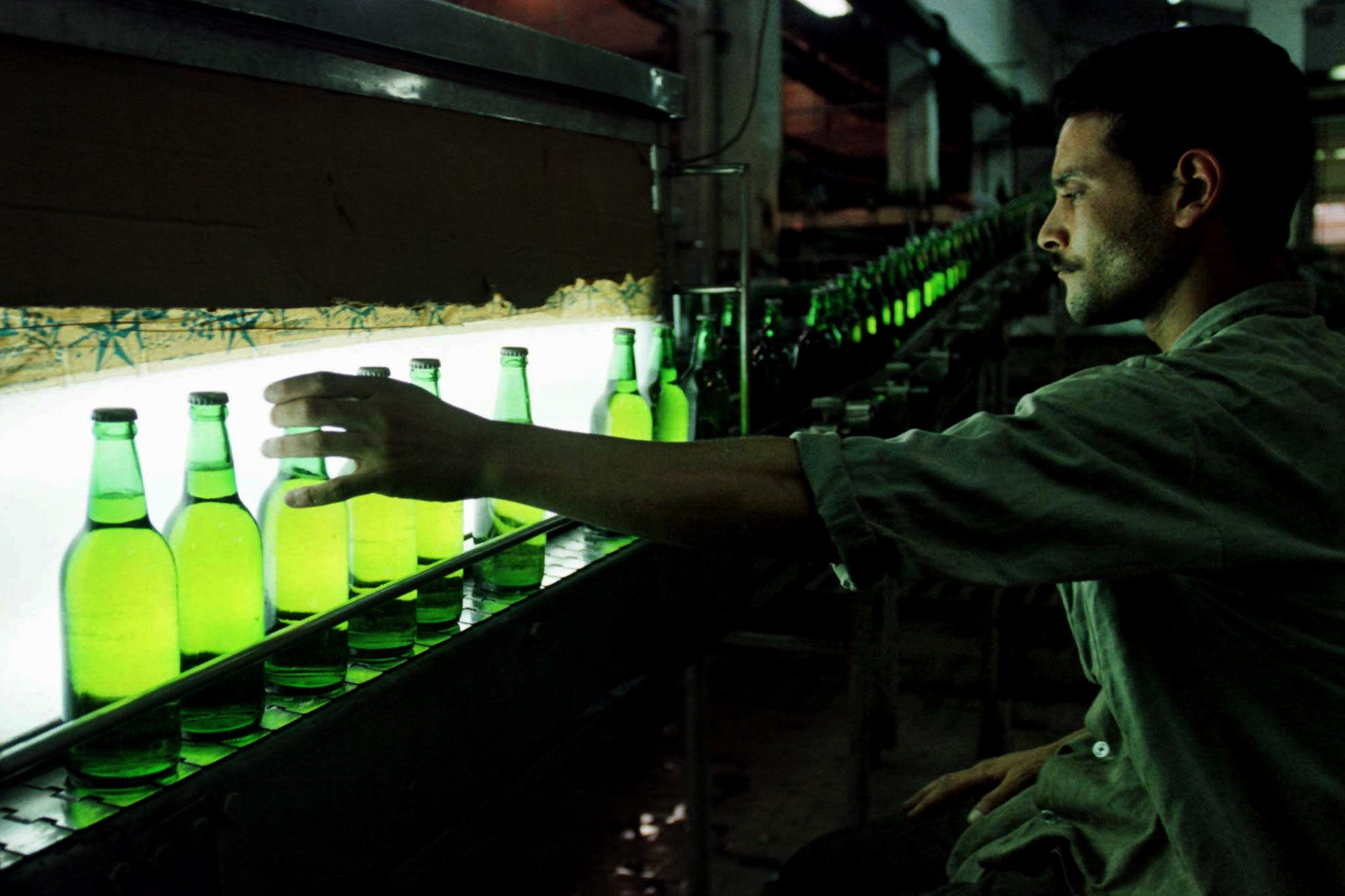 An Egyptian worker inspects a bottle of Stella beer rolling down the line at a factory in Cairo. 