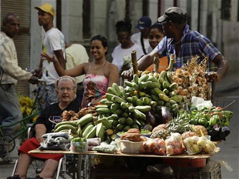 A man pushes his cart with vegetables and fruit for sale on a street in Havana. 