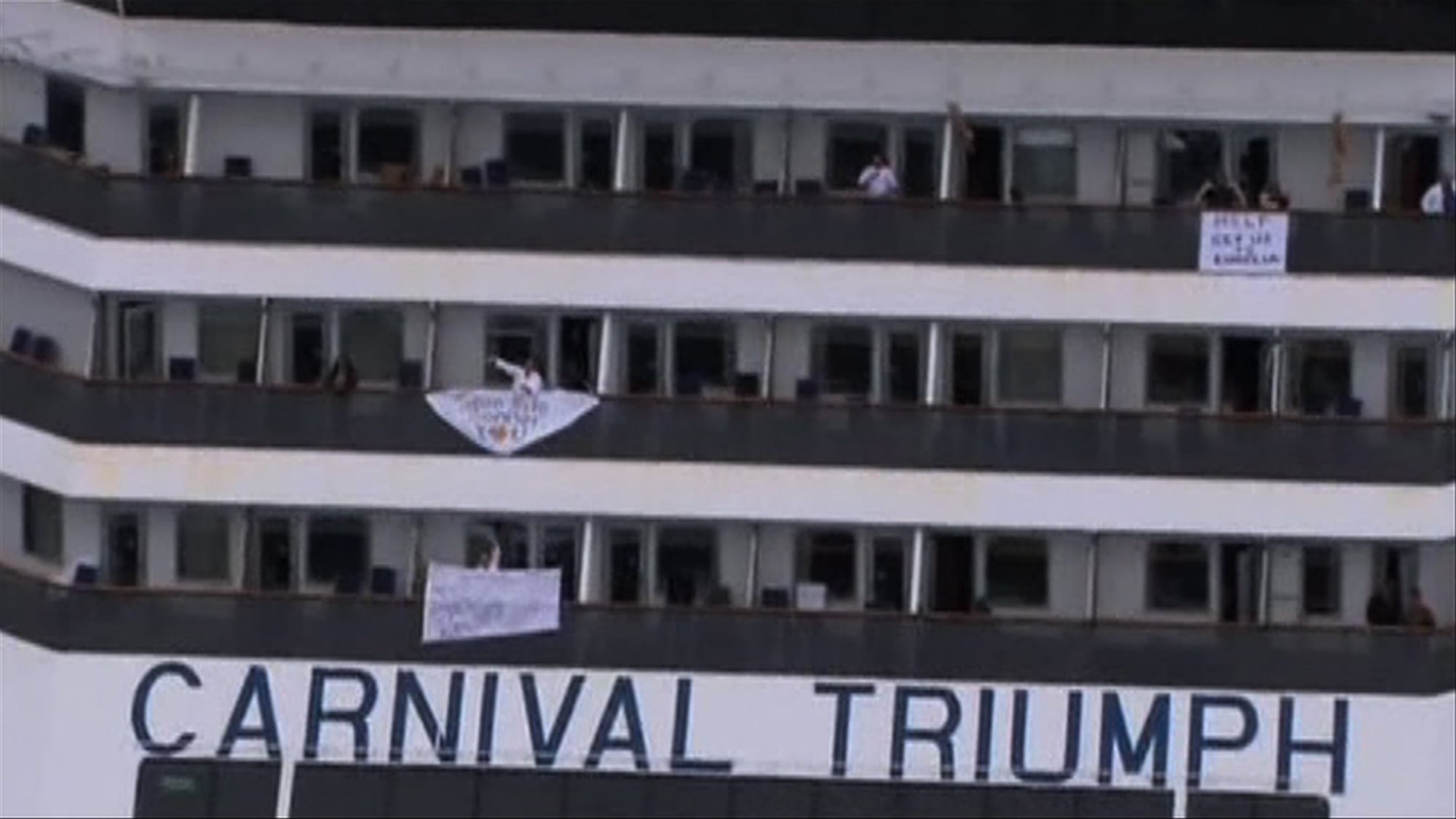 People wave and hang signs at the side of their balconies on the cruise ship Carnival Triumph cruise ship in this video frame grab from NBC News taken off the coast of Alabama, February 14, 2013. Three tugboats were hauling the disabled cruise ship Carnival Triumph cruise ship slowly into port in Mobile, Alabama, on Thursday where its arrival with more than 4,220 people aboard was expected later in the day, authorities said.