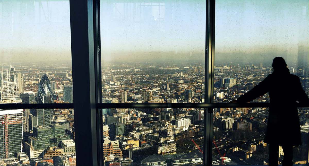 A woman looks out at the financial district from a window at the Shard in London. Shard is controlled by Qatar’s sovereign wealth fund. 