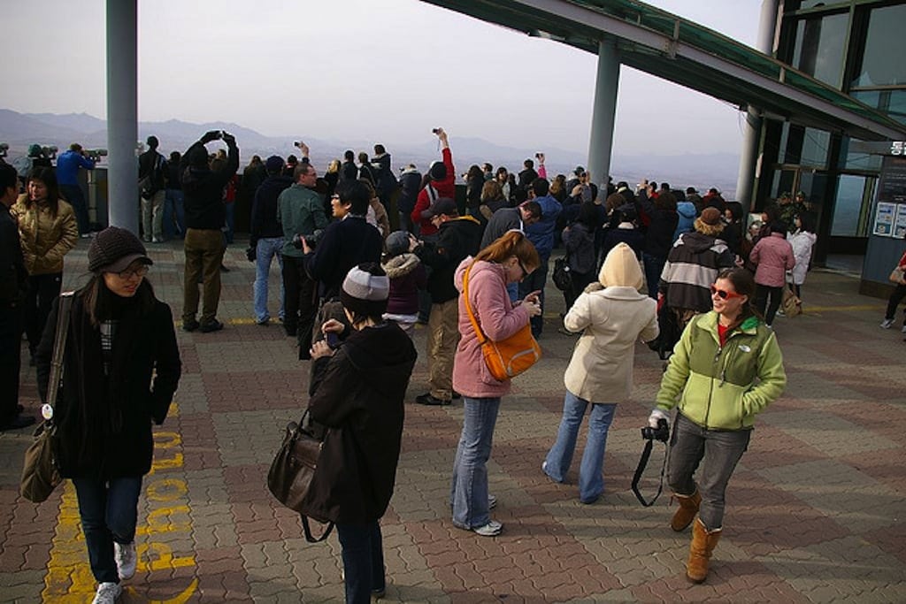 Tourists in South Korea take photos of North Korea from behind the designated camera line. 