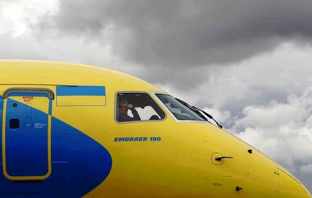 A crew member sits in the cockpit as an Embraer 190 is guided onto its stand ahead of the Farnborough Airshow 2012 in southern England July 7, 2012. 