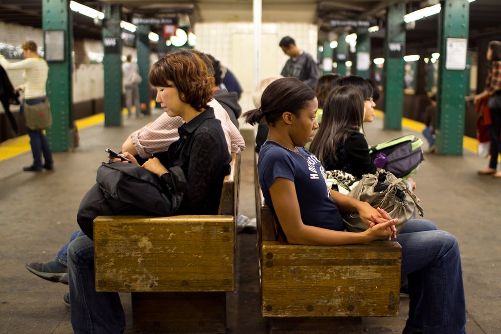 Two girls sit on the platform to wait for the subway in Manhattan. 