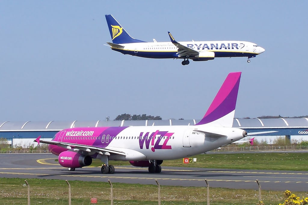 Ryanair 737 landing on a runway at Prestwick while a Wizz A320 HA-LPM waits at the holding point. 