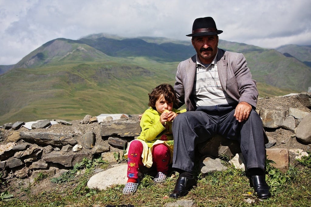 A tourist takes an Azerbaijani and his granddaughter, at the man's request. The man continues to offer him a cup of tea in typical Azerbaijani hospitality. 