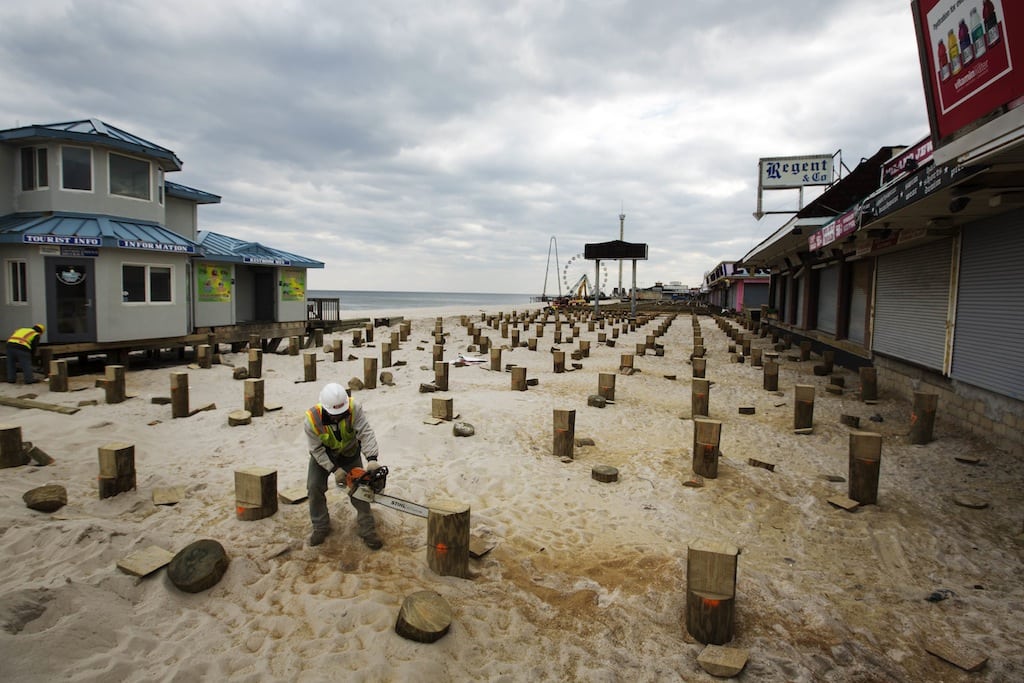A worker uses a chainsaw to trim new pilings for a replacement boardwalk, almost five months after Superstorm Sandy, in Seaside Heights, New Jersey March 22, 2013.