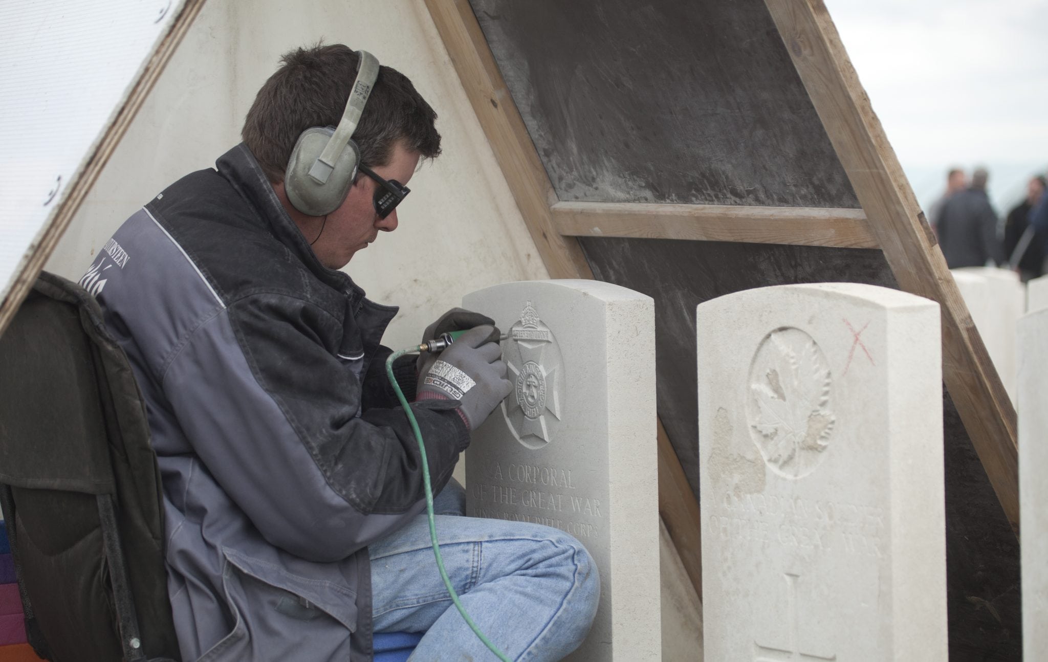 An engraver works under a rain tent as he re-engraves the headstone of a WWI soldier at Tyne Cot cemetery in Zonnebeke, Belgium on Monday, April 15, 2013. 