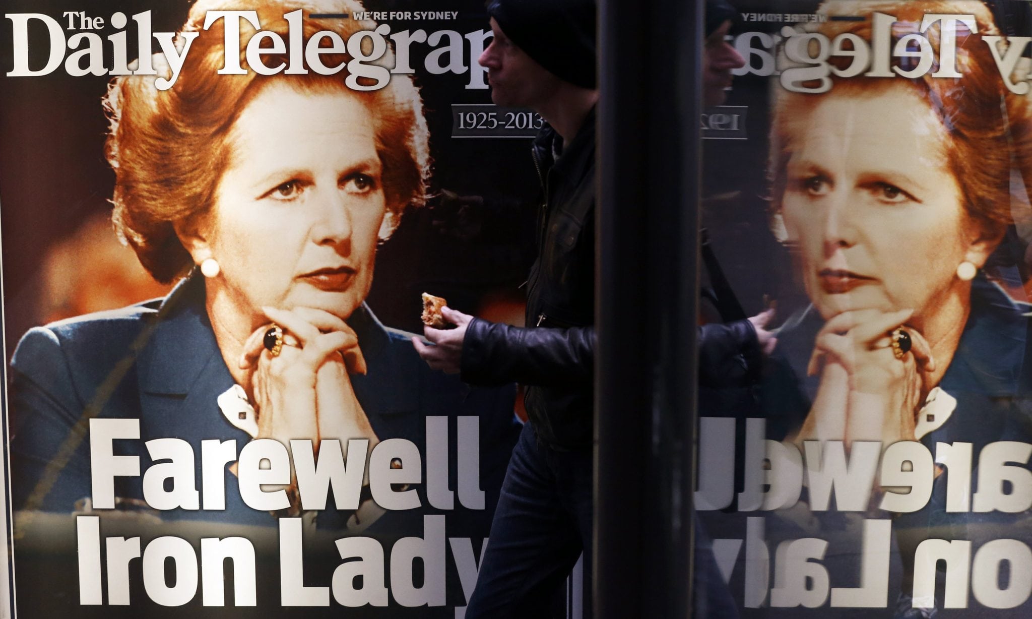 A man walks in front of a newspaper advertisement with the portrait of former British prime minister Margaret Thatcher in Sydney. 