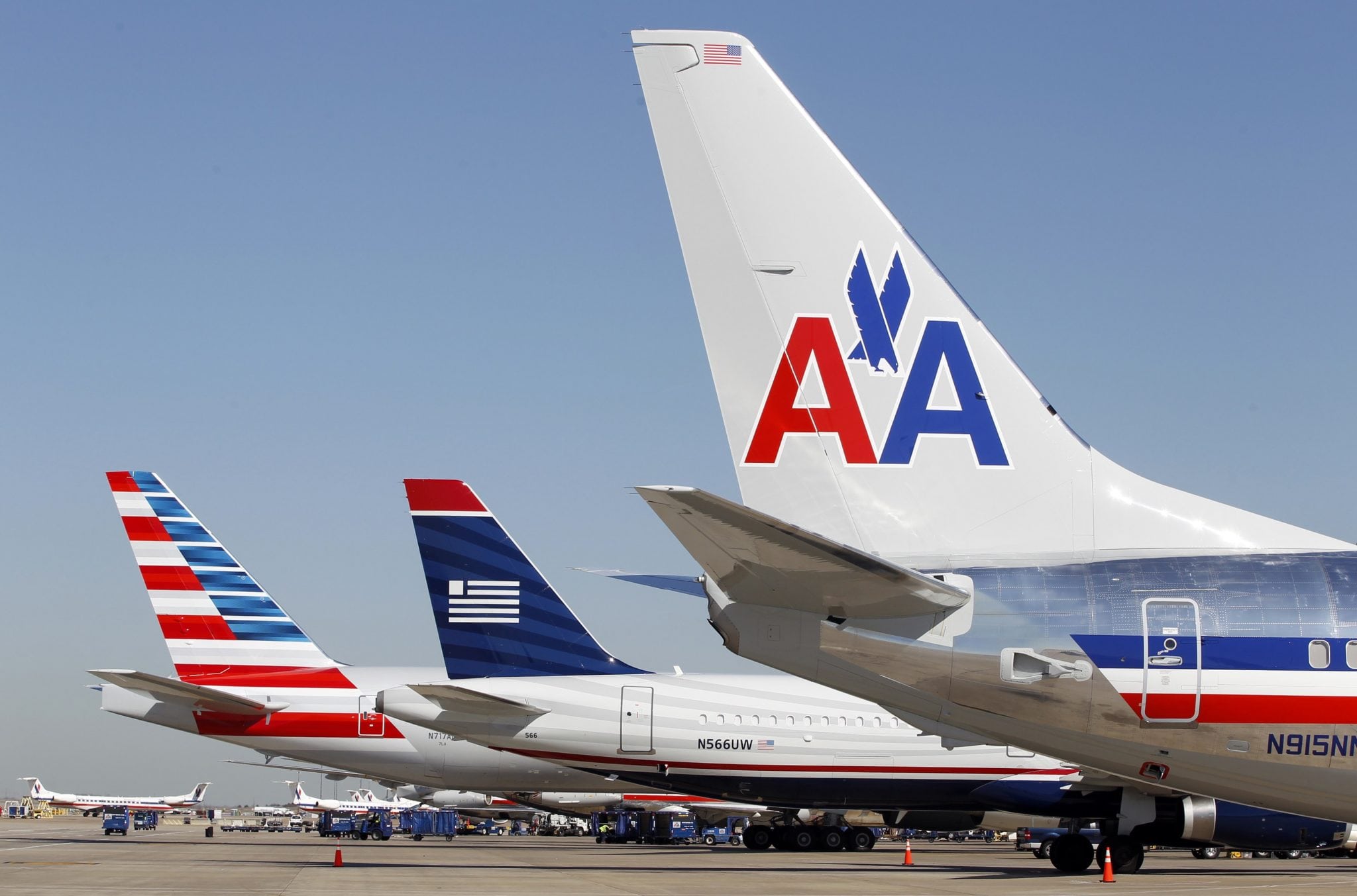 The tail sections of a newly designed American Airlines aircraft (L), a US Airways aircraft (C) and a traditional American Airlines aircraft are lined up at Dallas-Ft Worth International Airport February 14, 2013.