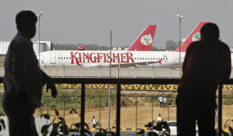 People are silhouetted as Kingfisher Airlines' aircrafts are seen parked at an airport in New Delhi October 1, 2012. 