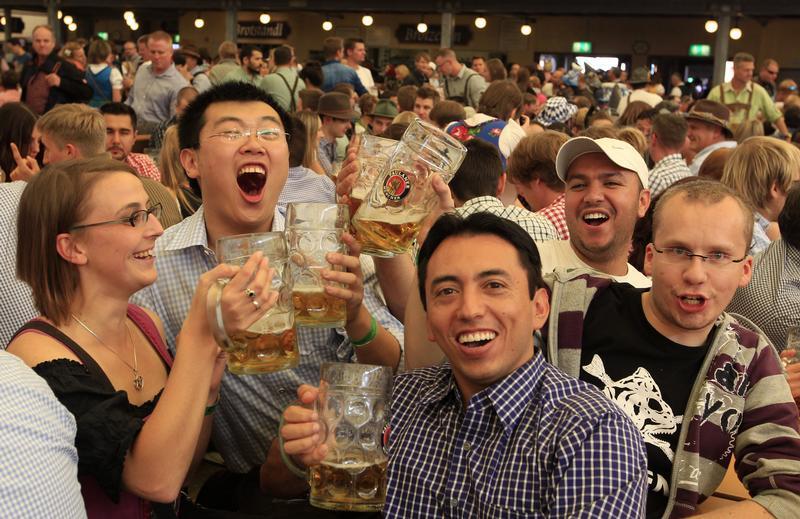 A Chinese tourist (foreground) grabs a beer and celebrates with German friends at Oktoberfest in Munich September 28, 2012.