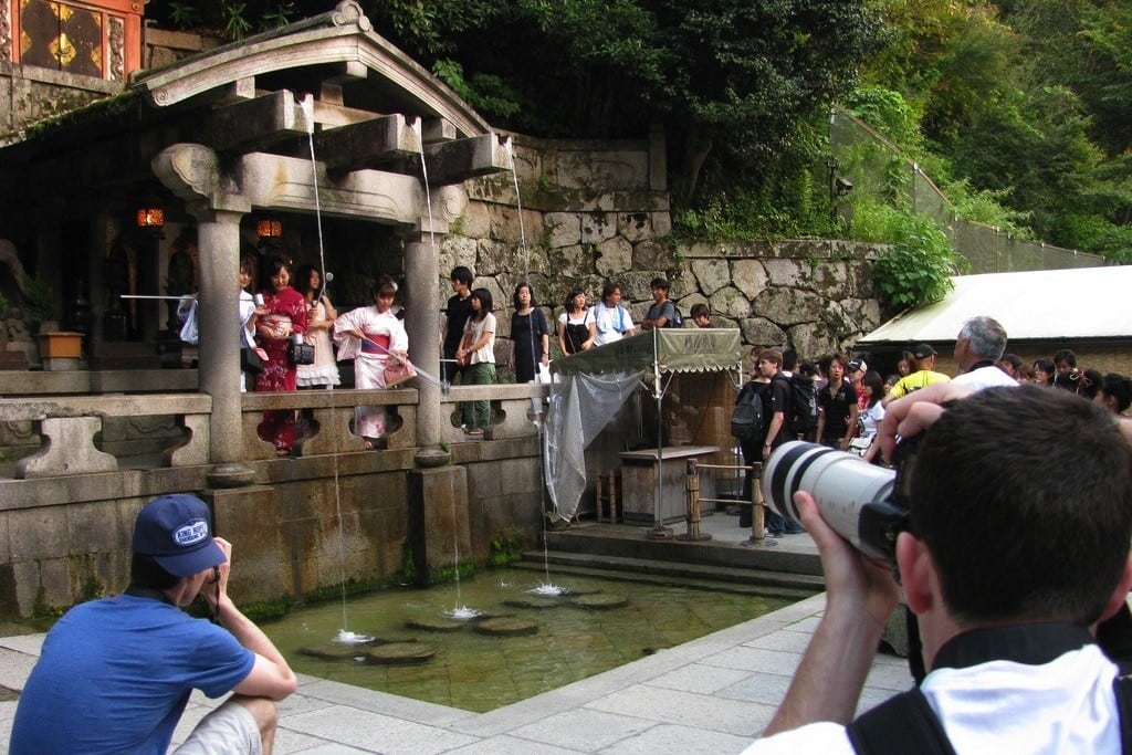 Tourists take photos at a traditional temple in Kyoto, Japan. 