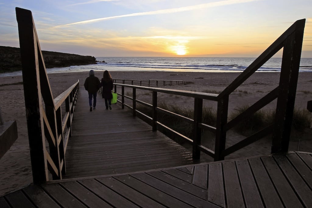 A couple walks to the beach during sunset at Lisandro beach on the Atlantic sea coast of Portugal, 40 km (25 miles) north of Lisbon March 20, 2013. 