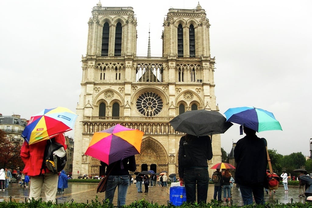 Tourists stand in the rain to watch the Notre Dame in Paris. 