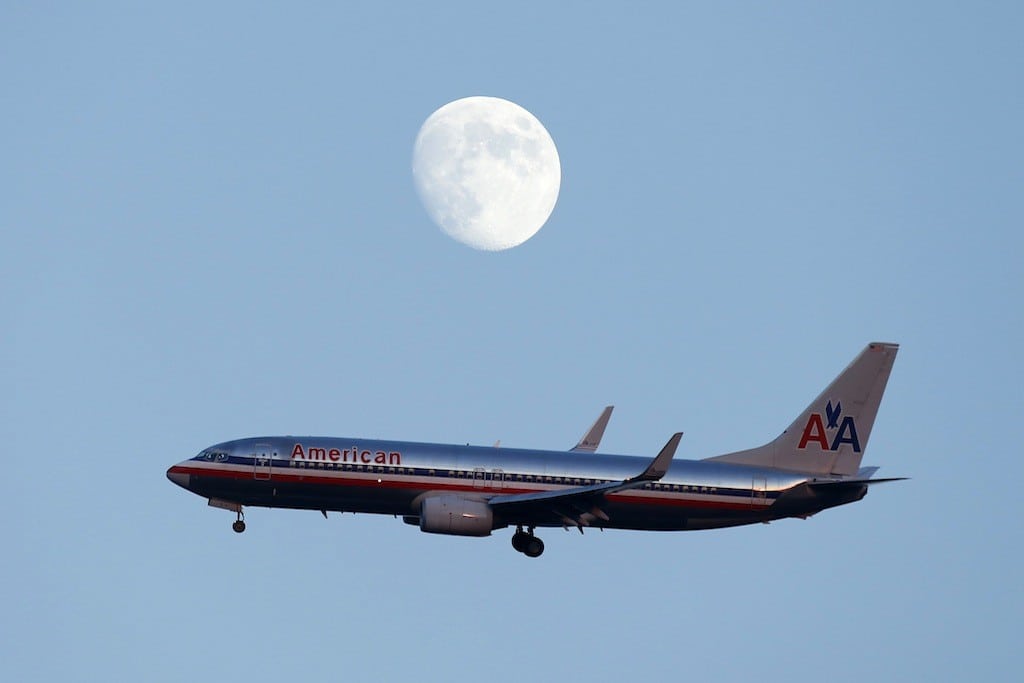 An American Airlines passenger jet glides in under the moon as it lands at LaGuardia airport in New York. 
