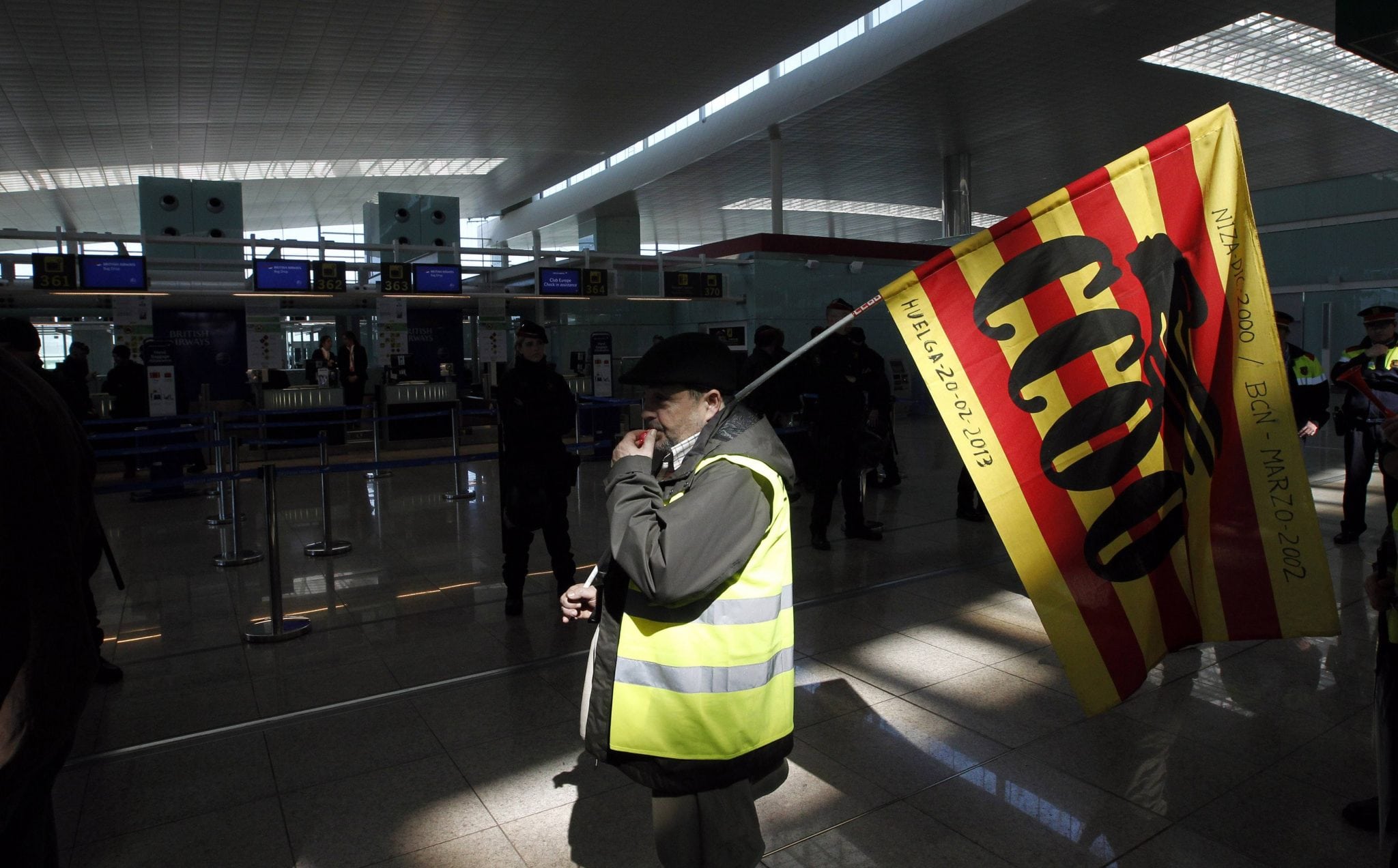 A man holding a Comisiones Obreras trade union flag walks past Iberia's check-in desk during an Iberia workers strike at Terminal 1 of Barcelona's airport. 