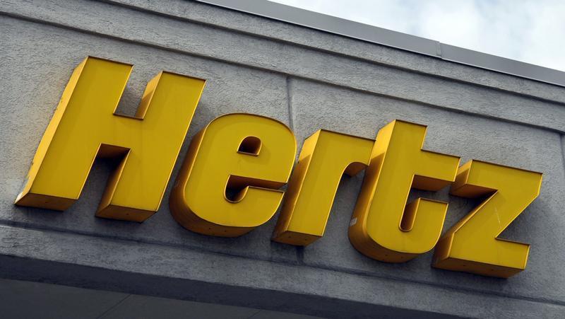 A Hertz sign outside an airport rental station. 